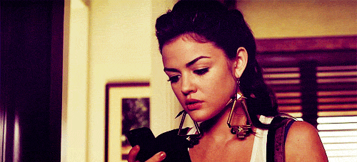 12 coisas que só mesmo quem tem irmãos entende Lucy Hale, em Pretty Little Liars, olhando para a tela do celular e depois com cara de espanto para a câmera
