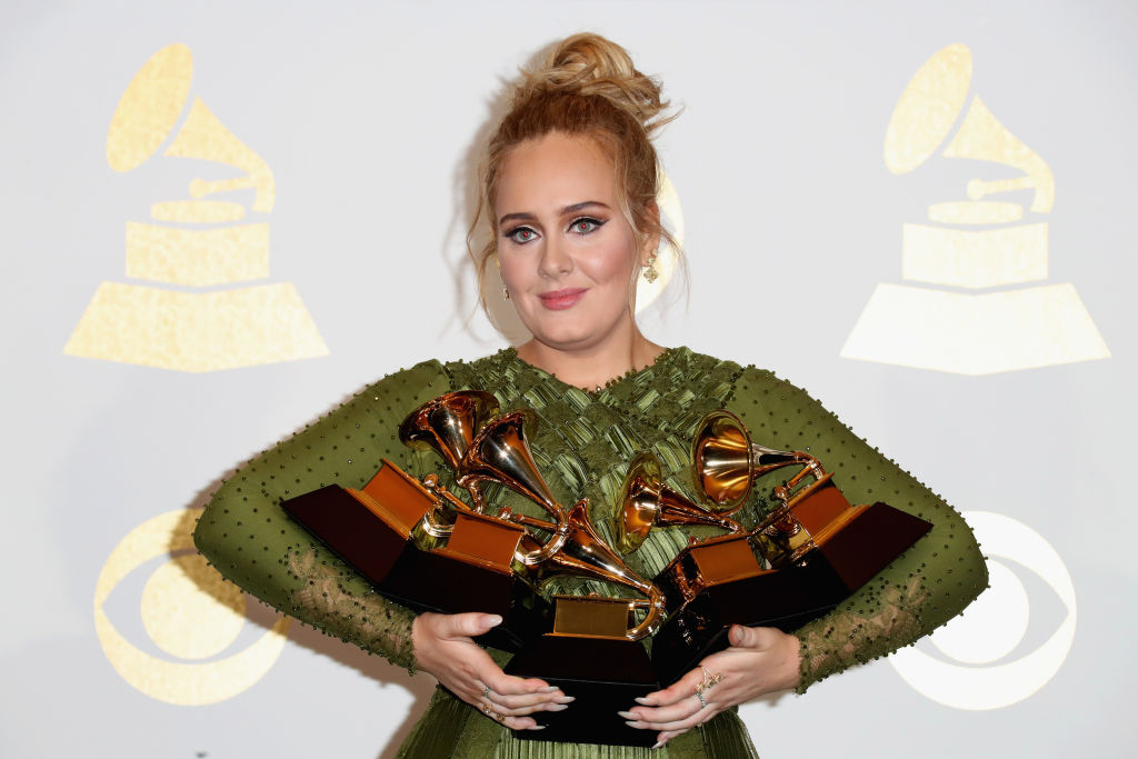 adele-grammy-awards Adele em tapete vermelho com vestido verde e cabelo preso exibindo os cinco prêmios que ganhou no Grammy Awards 2017