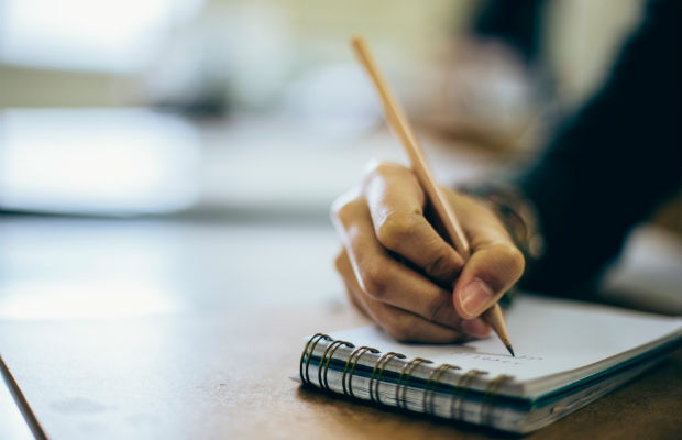 Menina escrevendo em caderno com lápis