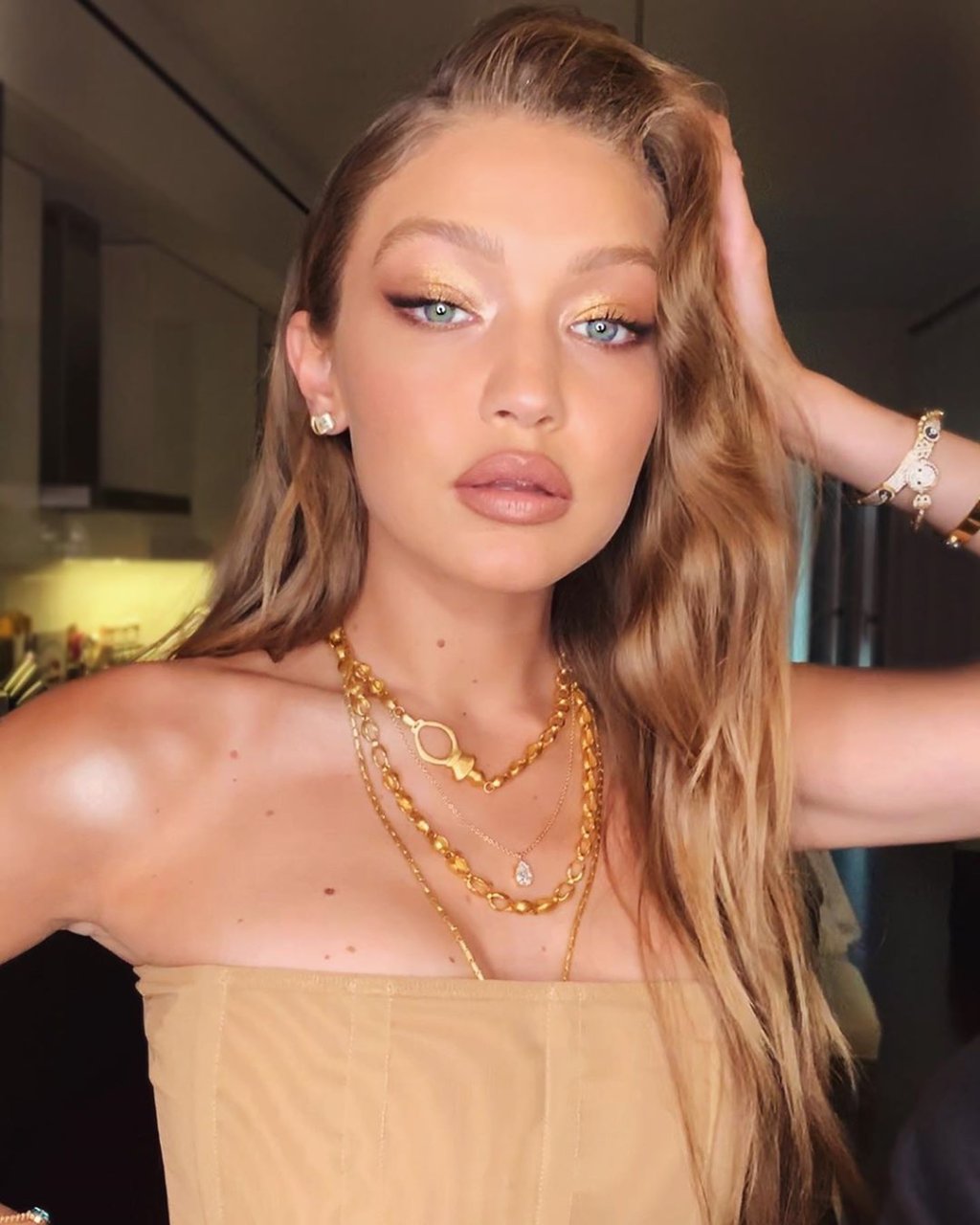 Gigi Hadid posando para foto; ela está com expressão séria e com uma das mãos apoiada na cabeça