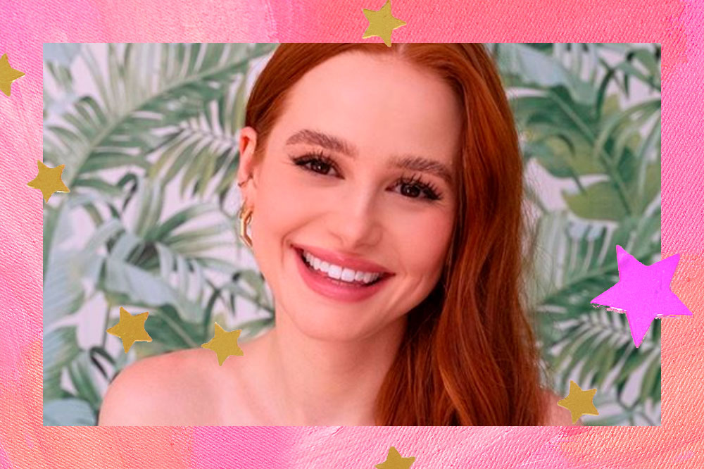 Madelaine Petsch sorrindo com o cabelo jogado para um lado. O fundo da montagem é rosa e tem estrelas douradas.