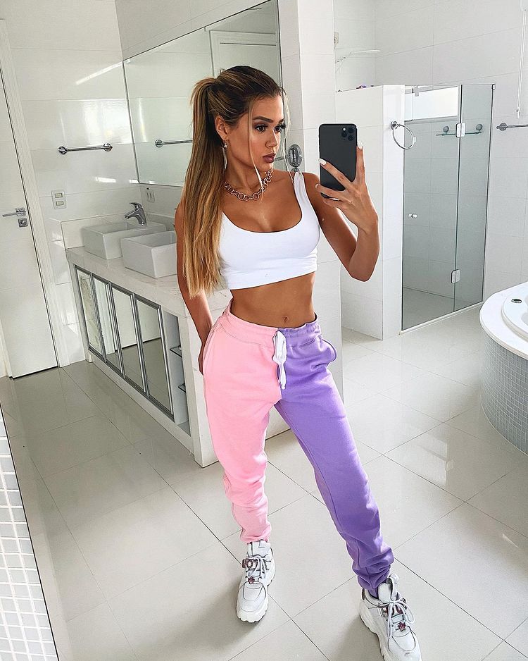 Influenciadora Franciny Ehlke usando top branco com calça de moletom metade rosa e metade lilás e tênis branco