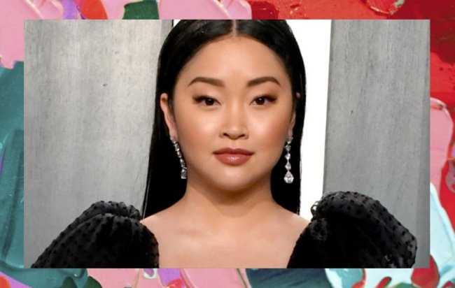 Lana Condor usando roupa preta de mangas bufantes e brincos compridos. Seu cabelo está solto e repartido ao meio. Ela olha para a câmera com expressão séria