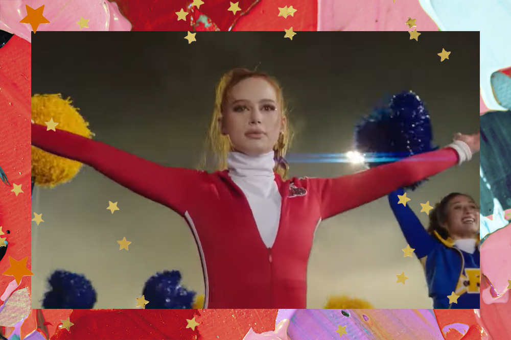 Cheryl Blossom usa casaco vermelho. Ela está com os dois braços abertos