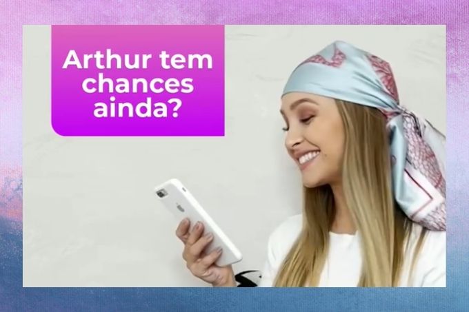 Carla Diaz usa lenço na cabeça, camiseta branca, sorri e segura celular. Na imagem está escrito "Arthur ainda tem chance?"