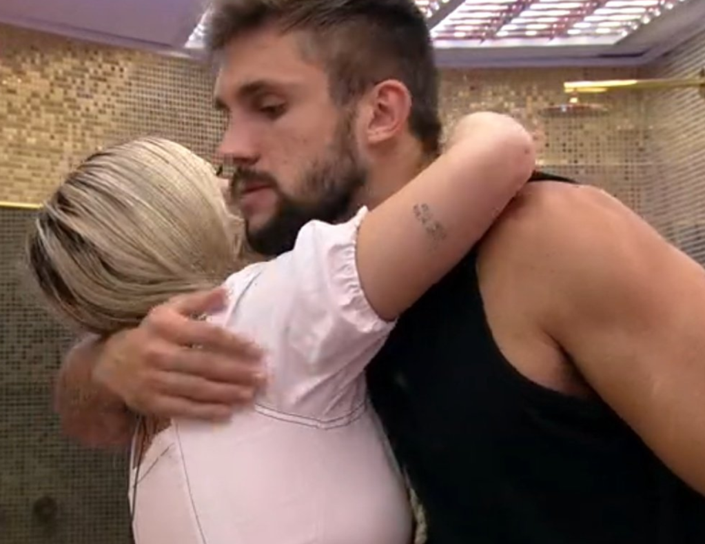 Viih Tube, de blusa branca, e Arthur, de regata preta, se abraçam no BBB21. Pela imagem, é possível ver apenas o rosto dele, que está com expressão séria