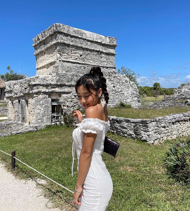 Heyoon, do Now United, com roupa branca no México, usando trança no cabelo preso em rabo de cavalo alto.