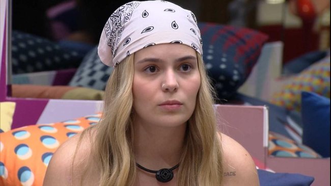 viih-tube-bbb21 Viih Tube olhando séria para algo ou alguém. Ela está com o cabelo solto e usa um lenço branco com estampas pretas amarrado na cabeça