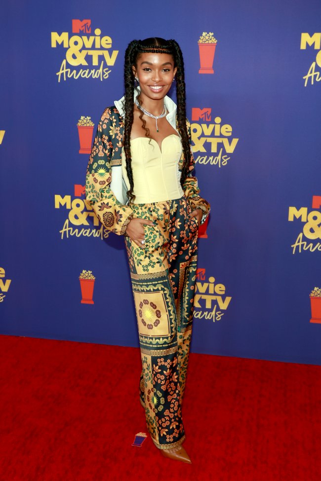 Atriz Yara Shahidi no MTV Movie & TV Awards, usando corset amarelo e conjunto estampado, posando com expressão sorridente.