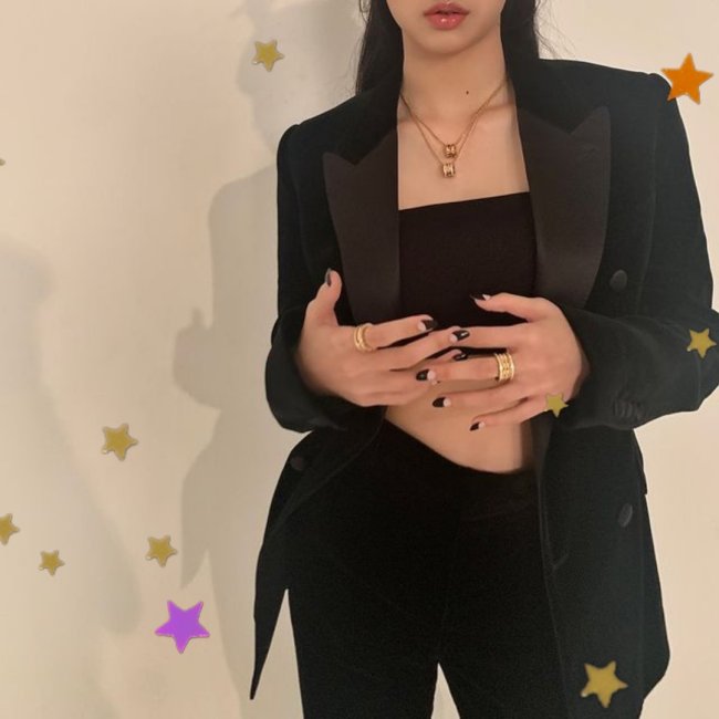 Lisa, integrante do grupo Blackpink, porém nesta foto não conseguimos ver seu rosto apenas da sua boca para baixo, ela posa segurando as mãos, usando blazer preto, calça preta e top.