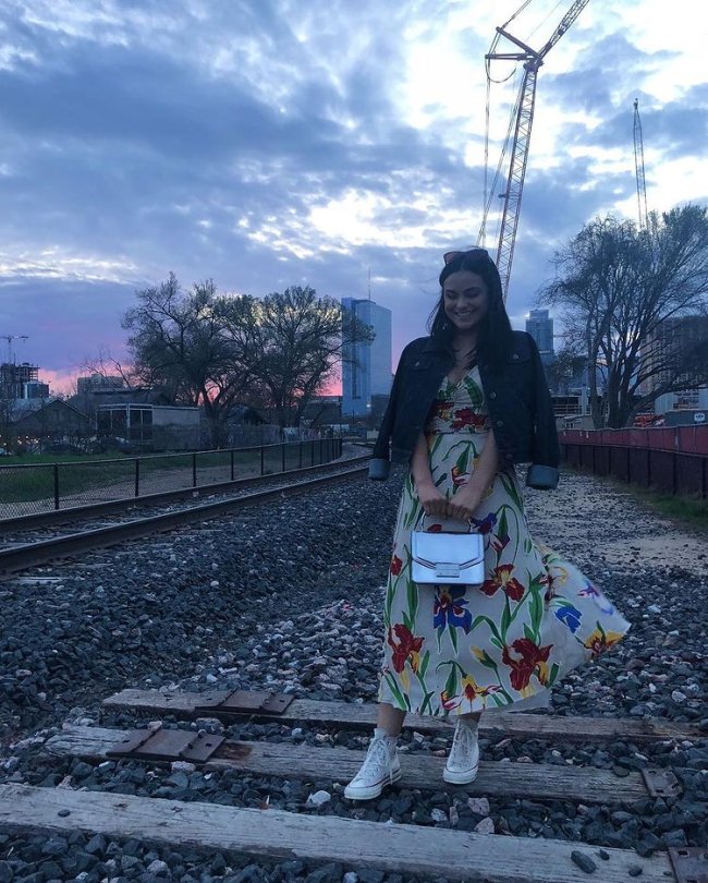 Camila Mendes com jaqueta jeans, vestido e tênis.