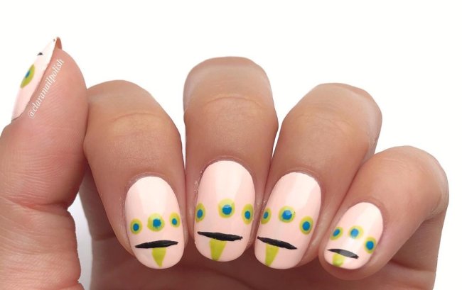 Foto com destaque nas unhas com nail art de bolinha, dessa vez formando um desenho de monstrinho com a língua para fora.