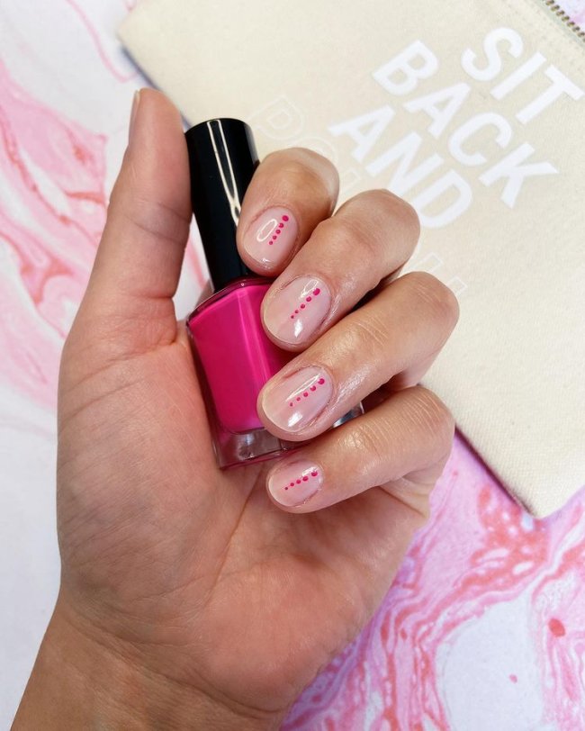 Foto com destaque nas unhas com nail art de bolinha, dessa vez com fundo transparente e bolinhas rosa.