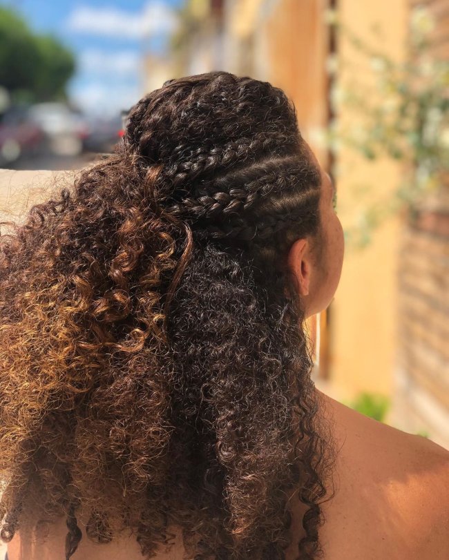 Jovem de costas exibindo seu penteado com trança meio preso.