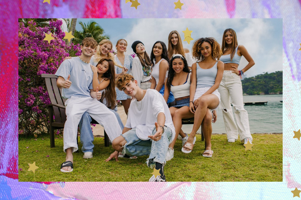 Grupo Now United em uma grama, no fundo há um lago