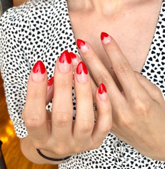 Foto com close nas unhas com desenho de coração vermelho na ponta de cada uma delas.