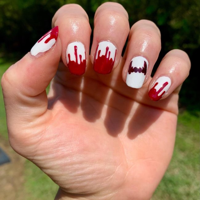 Foto com foco nas mãos exibindo a nail art das unhas. No caso, unhas brancas com detalhe de vermelho nas pontas.