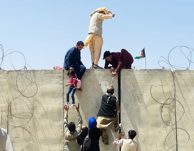 Afegãos escalam o muro do Aeroporto Internacional Hamid Karzai International, tentando pegar algum voo para fugir da capital Cabul, ocupada pelo Talibã