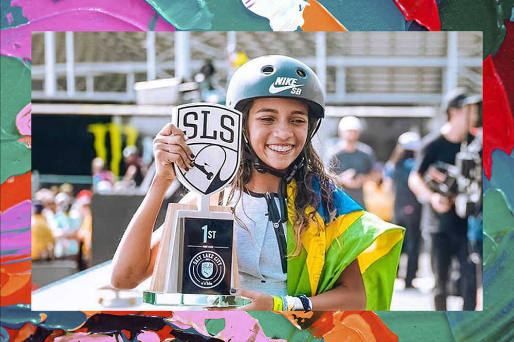 Foto da skatista Rayssa Leal vestindo um capacete, segurando a bandeira do Brasil e seu troféu de campeã nos EUA