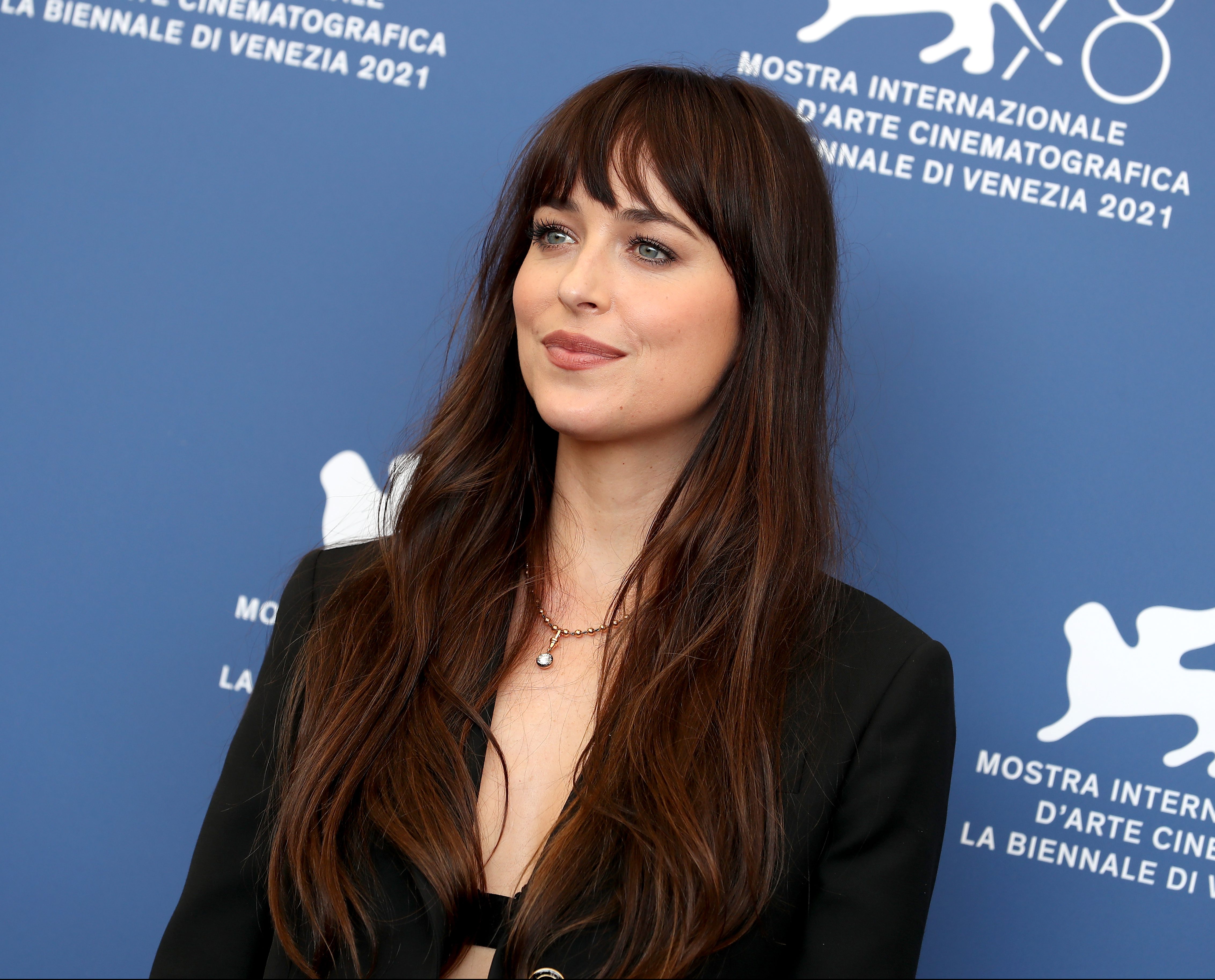 “The Lost Daughter” Photocall – The 78th Venice International Film Festival Dakota Johnson posando para foto com fundo azul e com expressão sorridente.