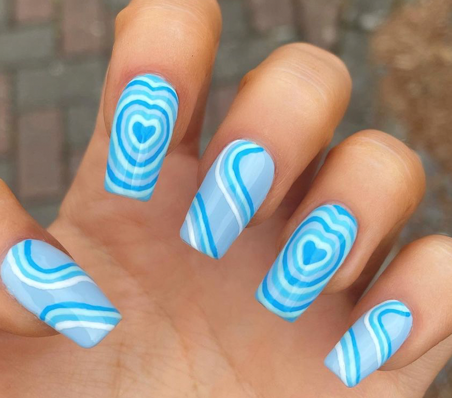 Foto com foco nas unhas exibindo a nail art chamada bubble heart, que traz vários corações um dentro do outro.