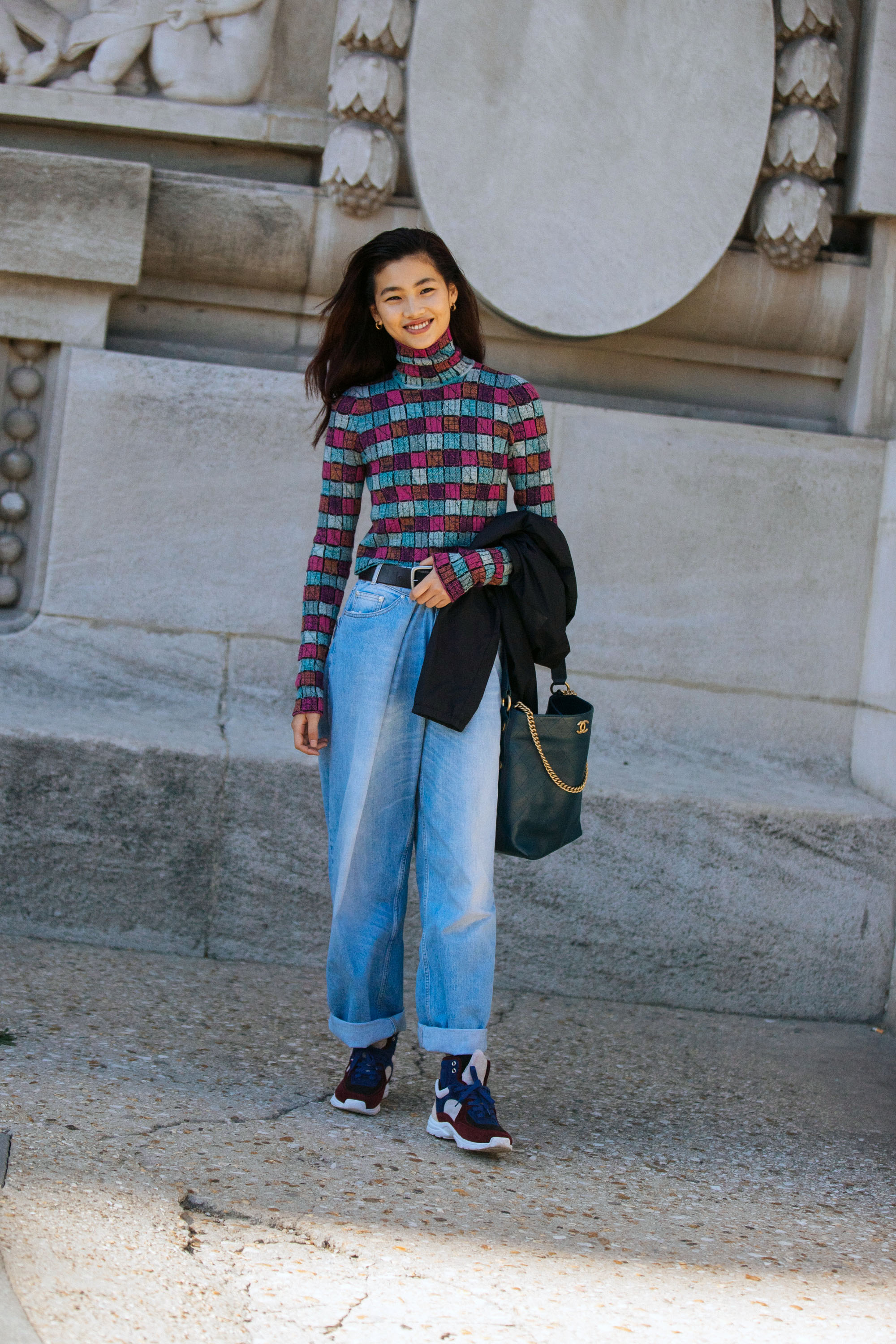 Jung Ho-yeon com calça jeans e tênis posando sorridente.