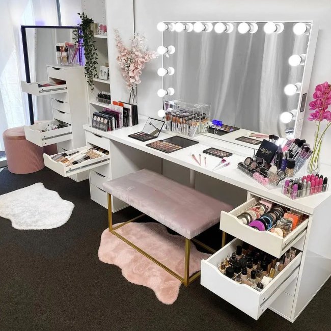 PENTEADEIRA COM ORGANIZADORES Imagem de uma penteadeira estilo camarim com as gavetas abertas e cheias de produtos de beleza.