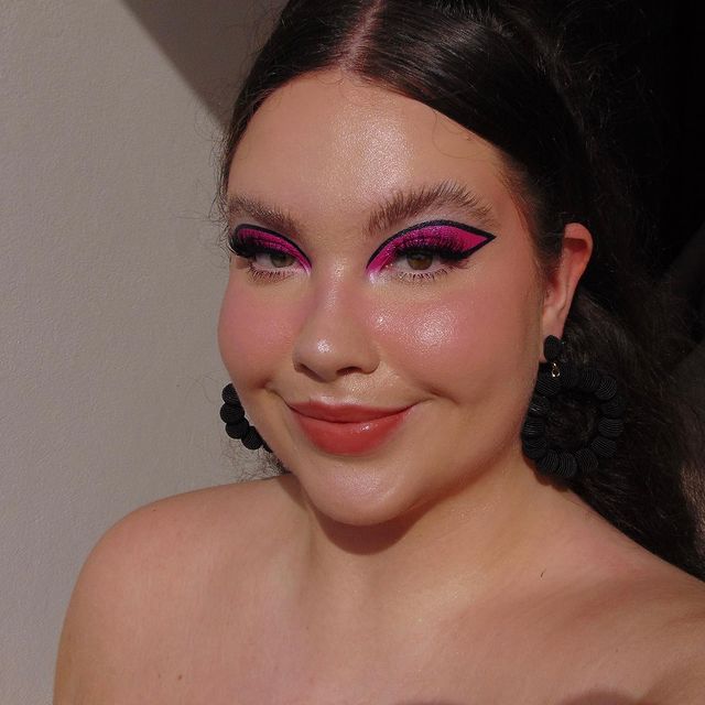 delineado banana rosa Selfie de uma mulher. Ela está com o cabelo preso, usa um brinco de argola preto e usa uma maquiagem básica com delineado preto banana e sombra rosa.