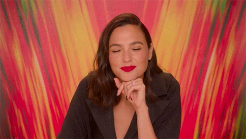 gal-gadot Gif de Gal Gadot. Nele, a atriz aparece de roupa preta, cabelos pretos e batom vermelho jogando as mãos para o lado em questionamento.