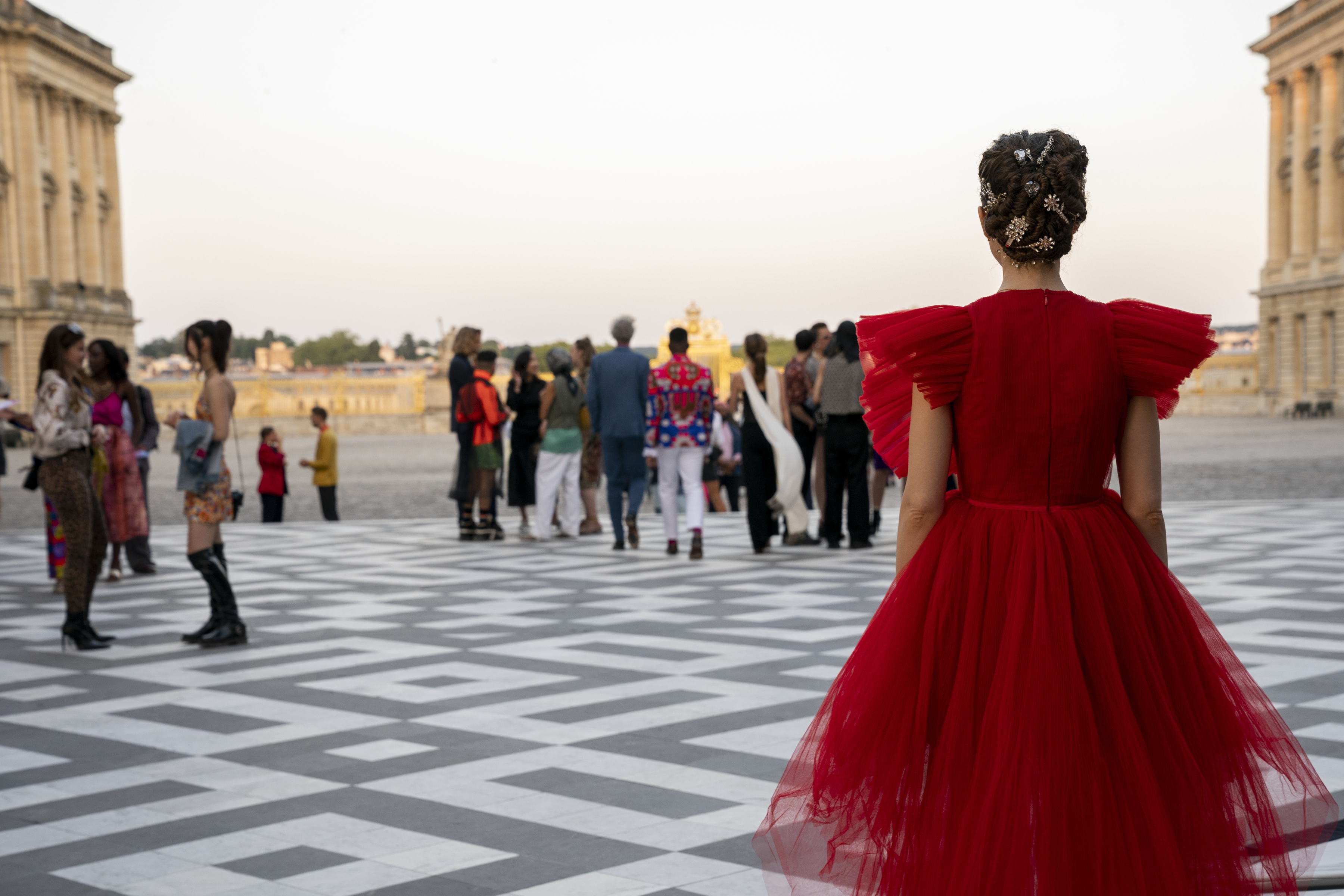 Lily Collins na série Emily em Paris de costas com vestido vermelho e cabelo preso em coque