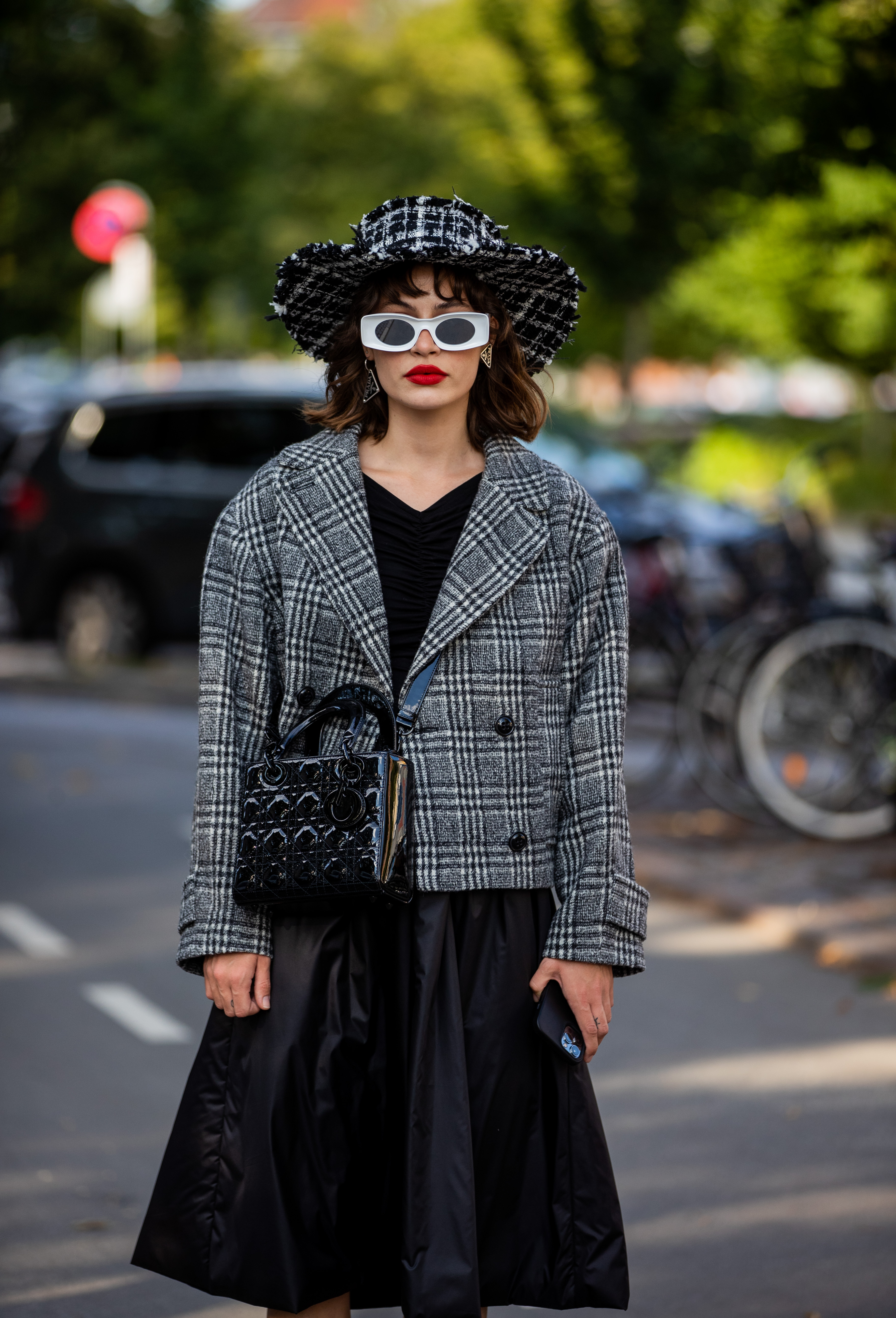 semana-moda-copenhagen Lele Berlin na semana de moda de Copenhagen, na Dinamarca usando chapéu preto e branco, óculos de sol branco, vestido preto, blazer preto e branco e bolsa preta atravessada no corpo