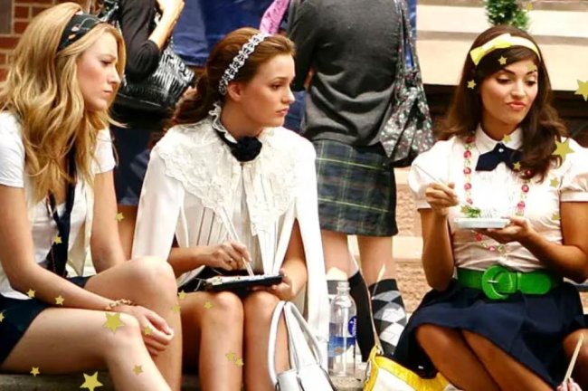 uniforme-gossip-girl Foto de uma cena de Gossip Girl com a Serena, Blair e outra personagens sentadas em uma escada de uniforme.
