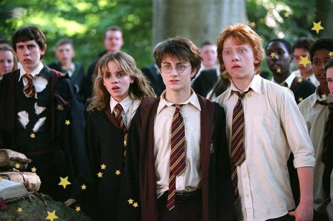 Cena de uma cena de Harry Potter com a Hermione, Harry e Rony. Os três estão lado a lado com expressões de surpresa e choque, usando uniformes da Grifinória.