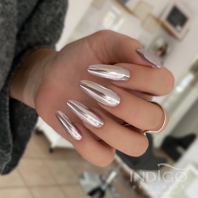 Foto de uma mão com unhas longas pintadas com esmalte metalizado.