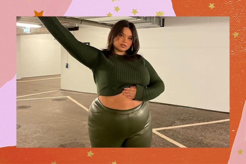 Montagem com o fundo colorido em tons de rosa e laranja com detalhes de estrelas douradas e foto de mulher no centro. Na foto, a mulher usa um cropped de manga longa verde, calça de couro verde e cabelo solto. Ela está com a mão esquerda na barriga e com a mão direita levantada. Ela olha para a câmera e não sorri.