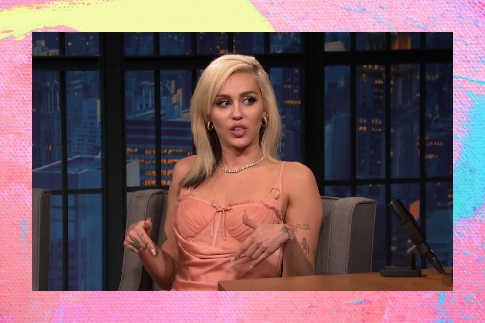 Miley Cyrus com vestido rosa sentada