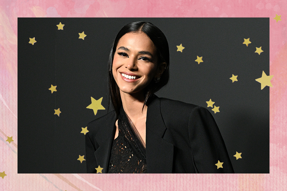 Montagem de foto da Bruna Marquezine em fundo rosa com estrelinhas douradas. Ela está sorrindo e usando um blazer preto oversized