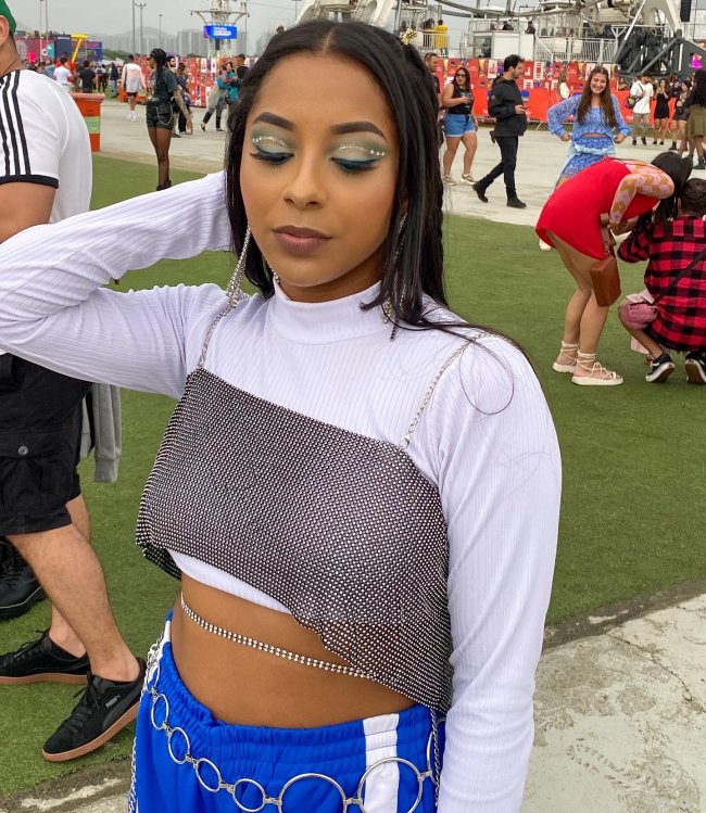 Foto da maquiagem de uma menina no Rock in Rio 2022. Ela está com sombra azul com aplicação de strass nos olhos. Ela olha para baixo e não sorri.