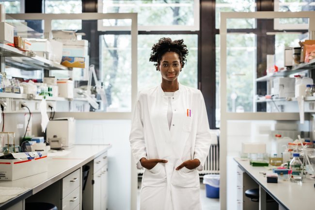 Pessoa cientista entre bancadas de laboratório