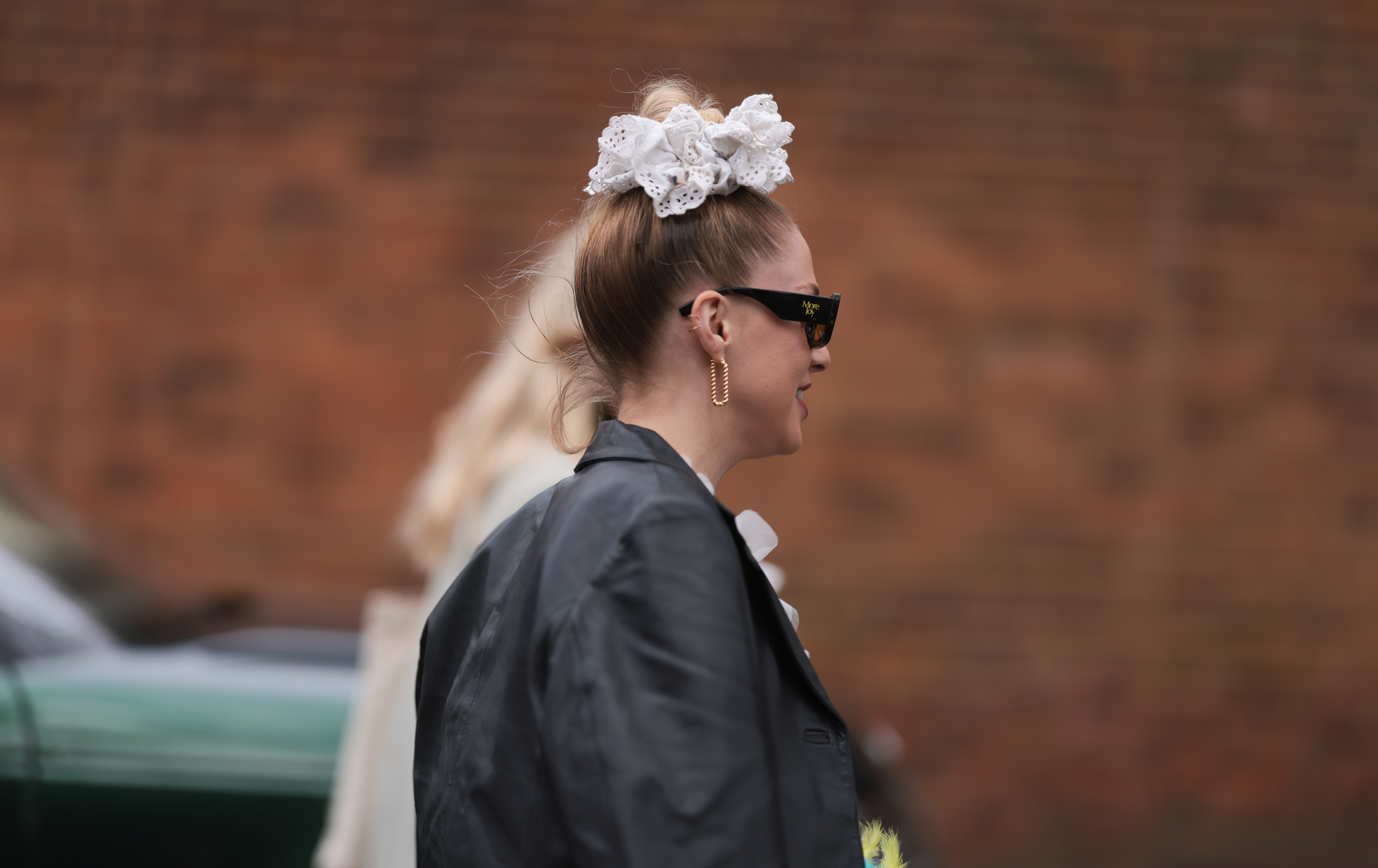 Street Style – LFW February 2023 Pessoa de costas usando cabelo preso em um coque alto com scrunchie branco no street style da semana de moda de Londres