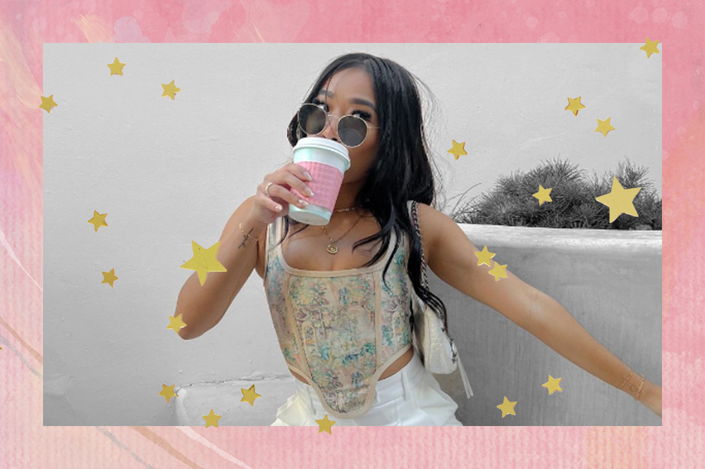 Garota usando óculos de sol, tomando café e usando corset com calça branca. Montagem em fundo rosa com estrelinhas douradas