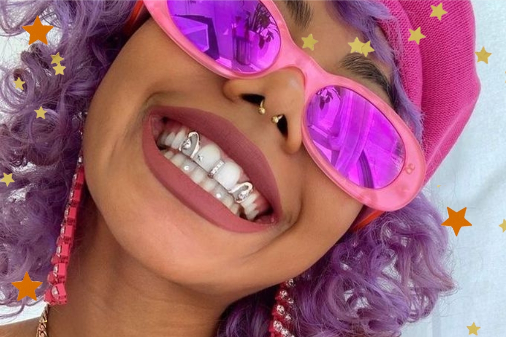 Foto de uma mulher com grillz nos dentes com detalhes de estrelas nas bordas.