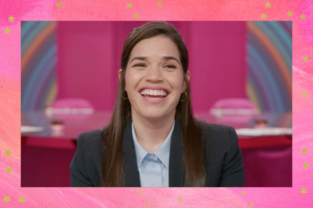 America Ferrera sorrindo enquanto dá entrevista sobre Barbie em um fundo na cor rosa com um arco-íris e um céu azul; a margem é uma textura em tons de rosa e branco com estrelas amarelas como decoração