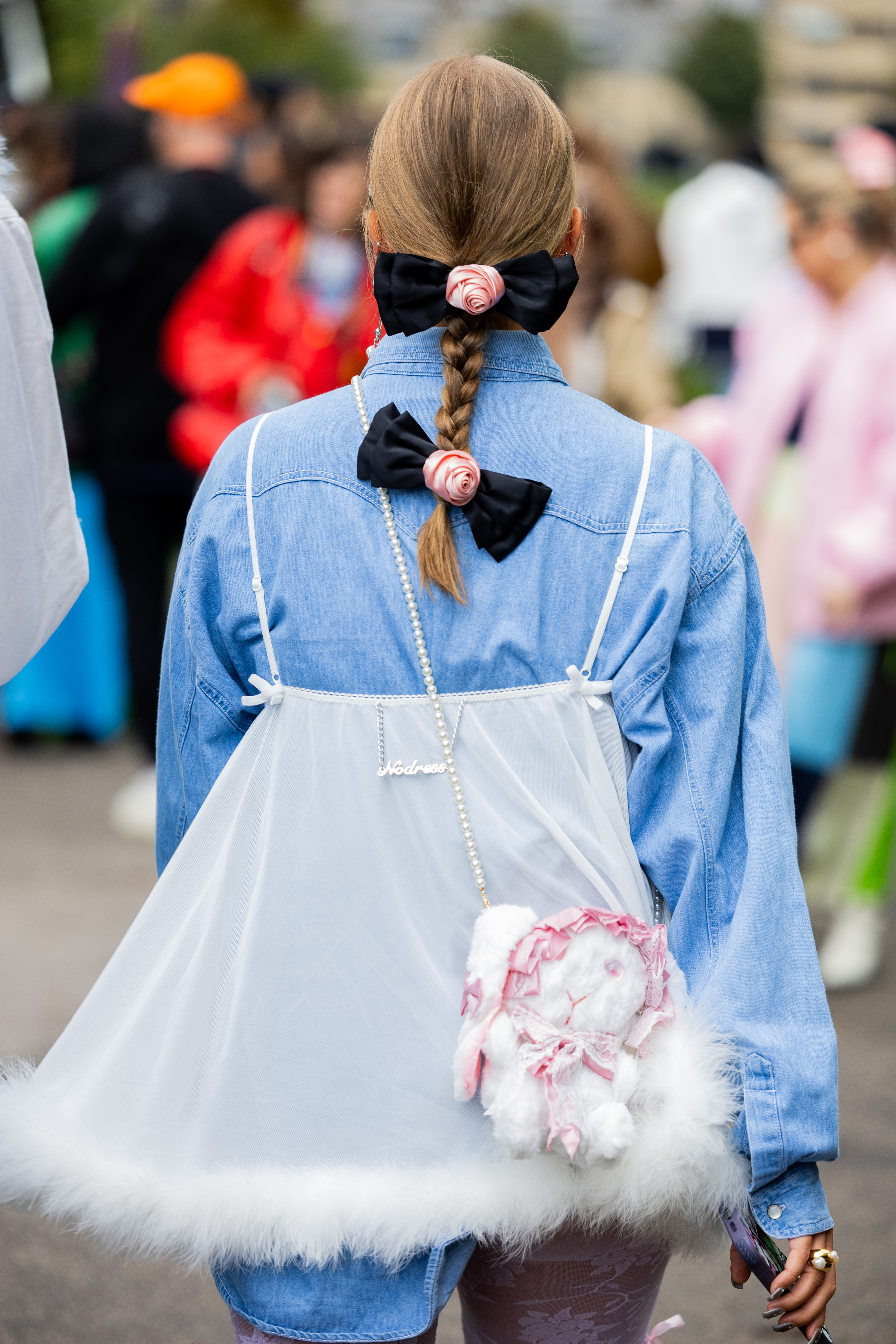 Street Style – Day 3 – Copenhagen Fashion Week Spring/Summer 2024 Pessoa usando trança no cabelo com laços pretos e flores rosas aplicados na semana de moda de Copenhagen na temporada de primavera-verão 2024