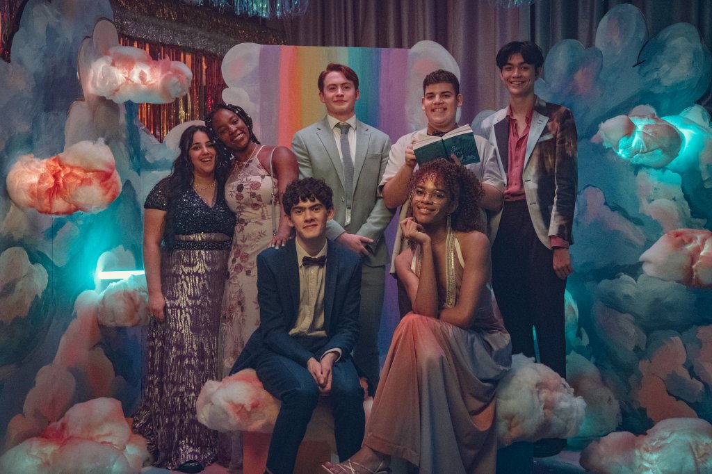 Elenco de Heartstopper posando para foto no baile com um fundo colorido e decorado com balões