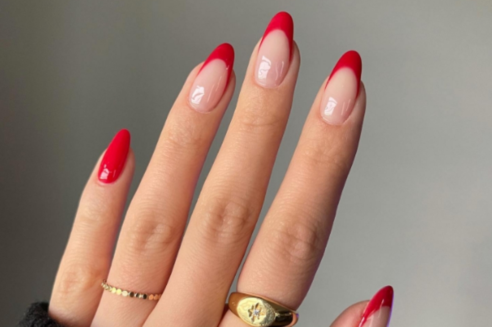 Mão com unhas francesinhas pintadas de esmalte vermelho