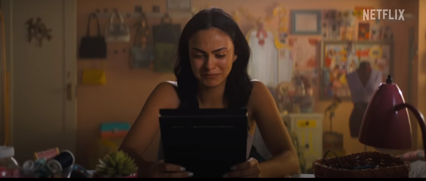 Imagem da atriz Camila Mendes no filme 'Justiceiras', no centro de um quarto chorando olhando para um porta-retrato.