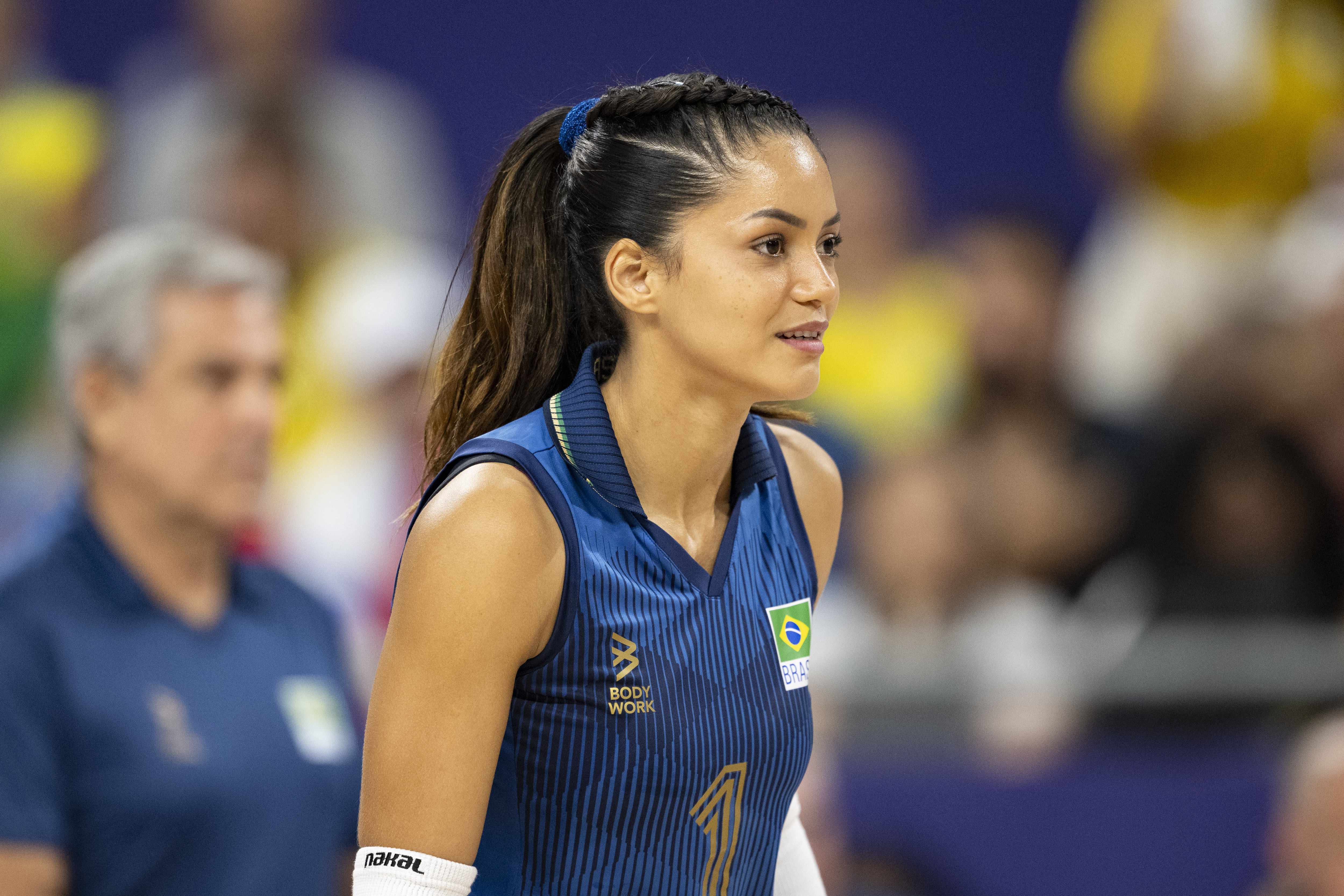 Imagem da jogadora de vôlei Nyeme, vestindo uniforme azul escuro e com um rabo de cavalo.