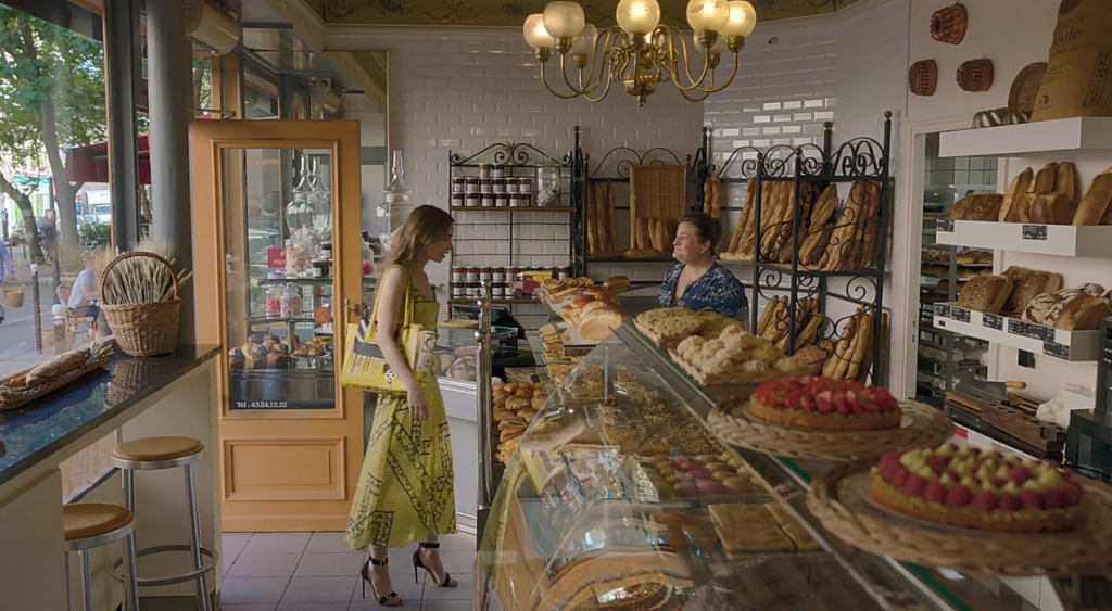 Cena de Emily em Paris, com Emily entrando em uma padaria cheia de doces.