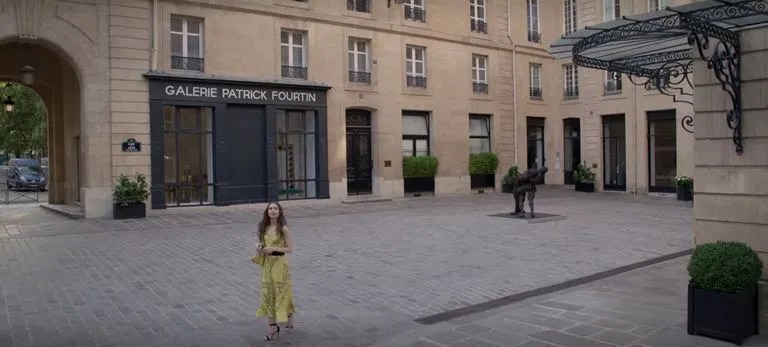 Cena de Emily em Paris, com Emily saindo do prédio onde mora.